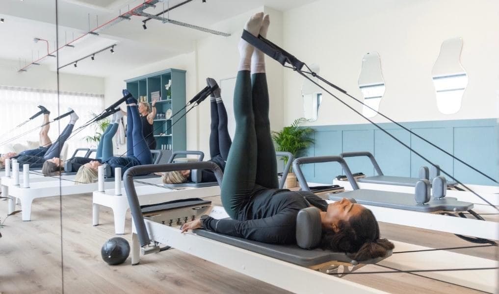 Beginners reformer class at Studio Core, four members lying with legs in the straps